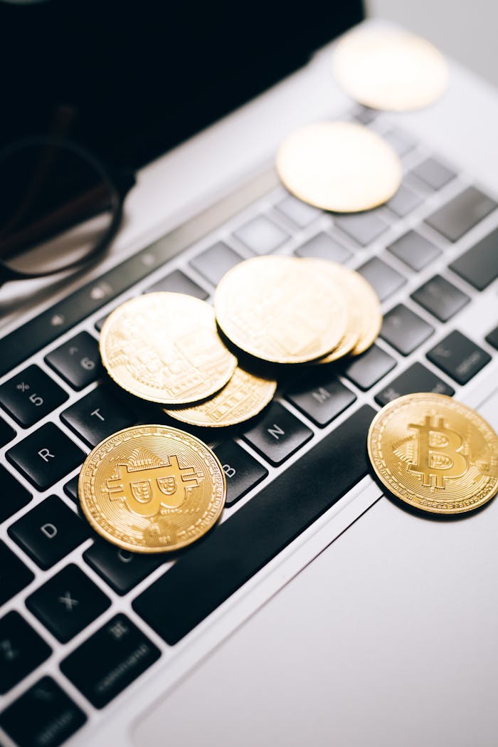 Closeup of gold bitcoins scattered on a laptop keyboard, symbolizing digital finance.